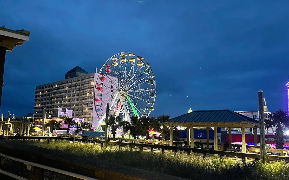 Carolina Beach Boardwalk at dusk with Ferris wheel and amusement rides lit up