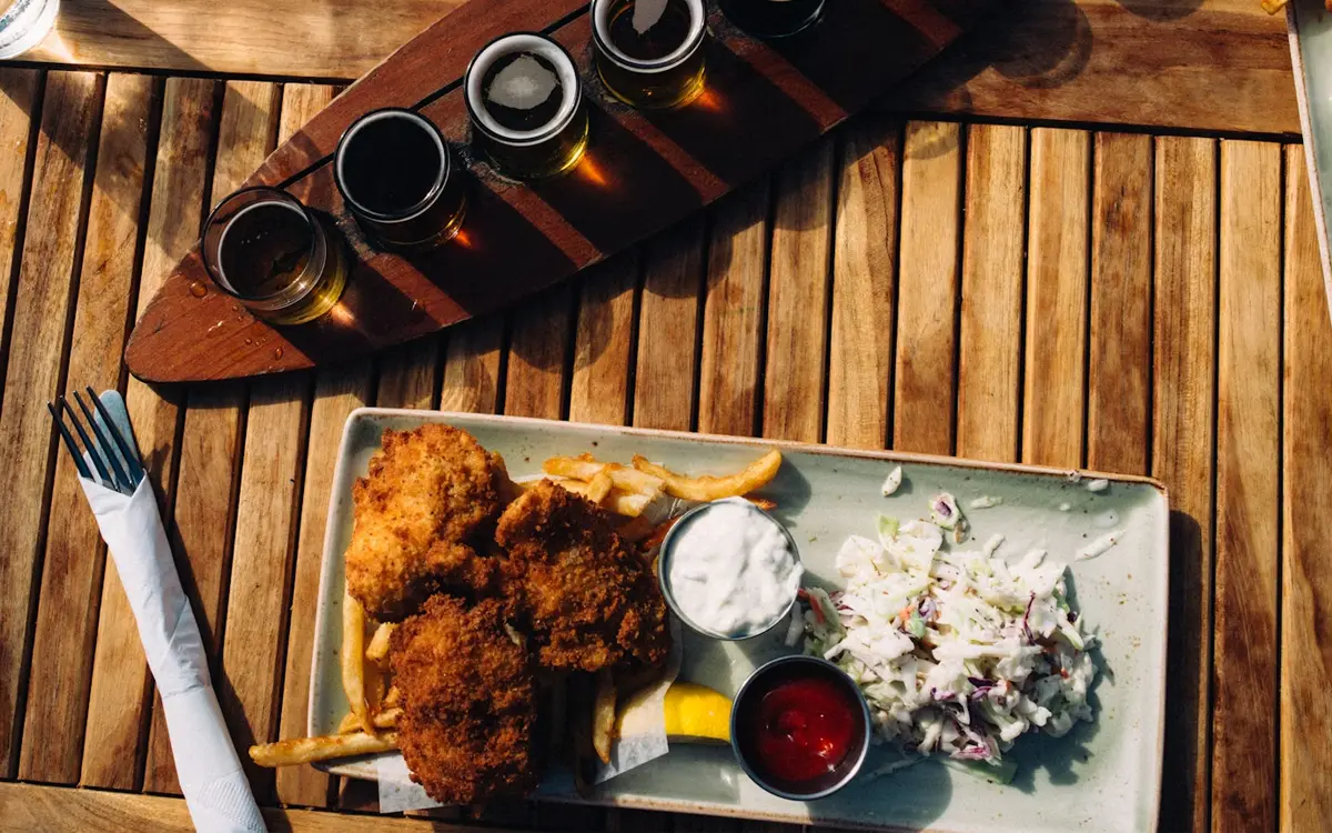 Fish and chips plate with coleslaw and a beer flight at a brewery