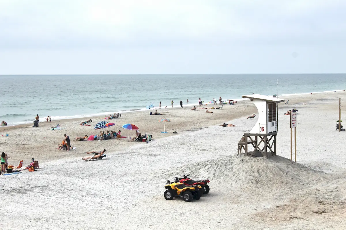 Beachgoers and lifeguard stand at Wrightsville Beach NC with ATV on the sand